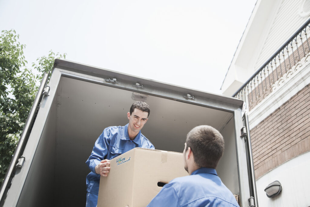 Male movers unloading a cardboard box out of a moving van